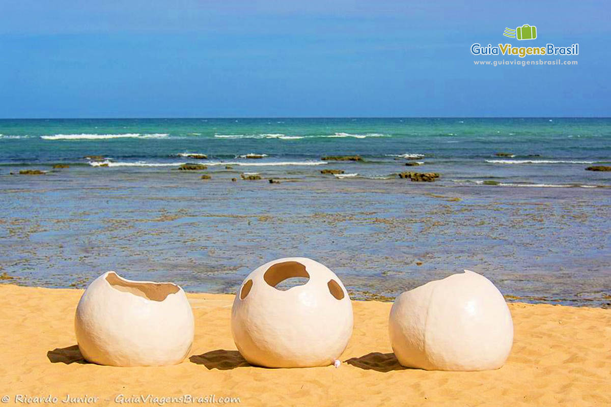 Imagem de esculturas imitando ovos de tartaruga na areia da Praia do Forte.